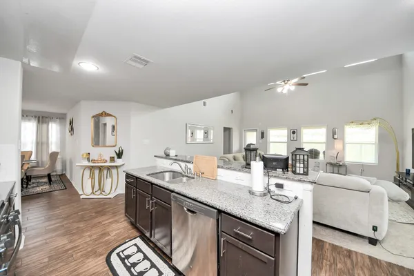 a large kitchen with granite countertop lots of counter top space a sink and stainless steel appliances