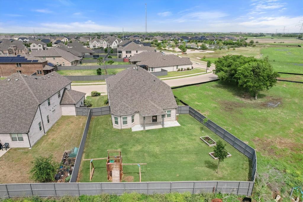 6910 Prairieside Trail Venus, TX 76084 - Photo 3 of 40 Expansive backyard featuring a covered patio, a wooden playset, and raised garden beds, all enclosed by a fence.