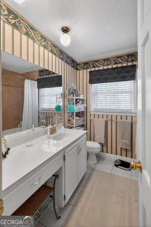 a bathroom with a granite countertop sink a toilet and a window
