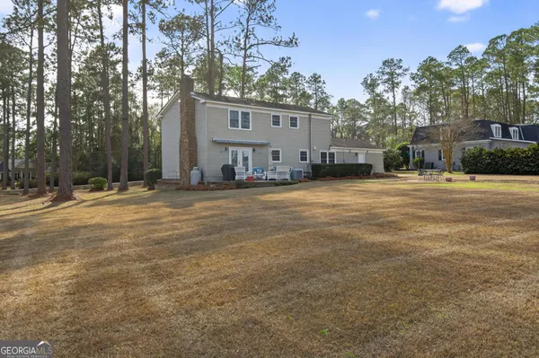 a backyard of a house with large trees and outdoor seating