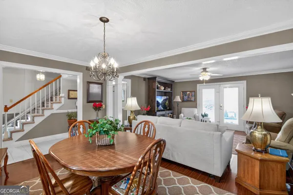 a living room with dining table and a chandelier