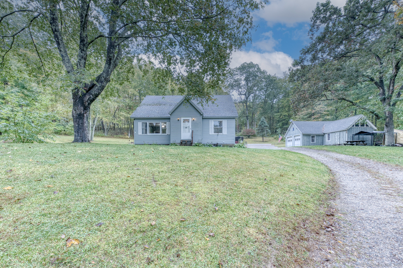 a front view of a house with a garden and tree