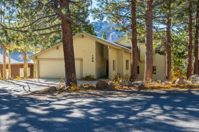 a view of the house with yard and trees in the background
