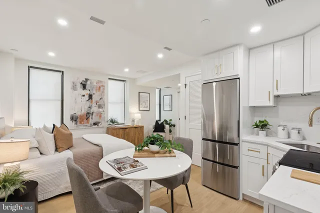 a living room with furniture a refrigerator and a dining table with wooden floor
