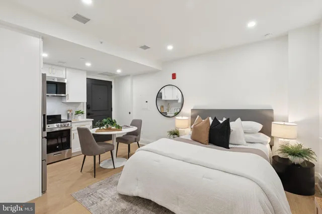 a bedroom with a bed a table and a potted plant