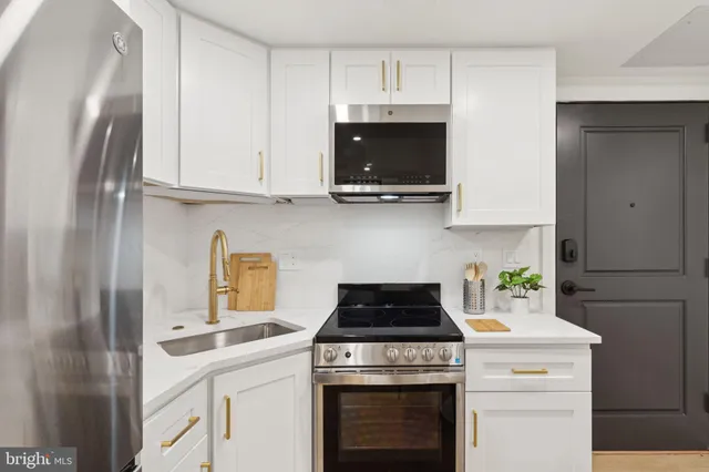 a kitchen with stainless steel appliances granite countertop white cabinets a stove a sink and dishwasher