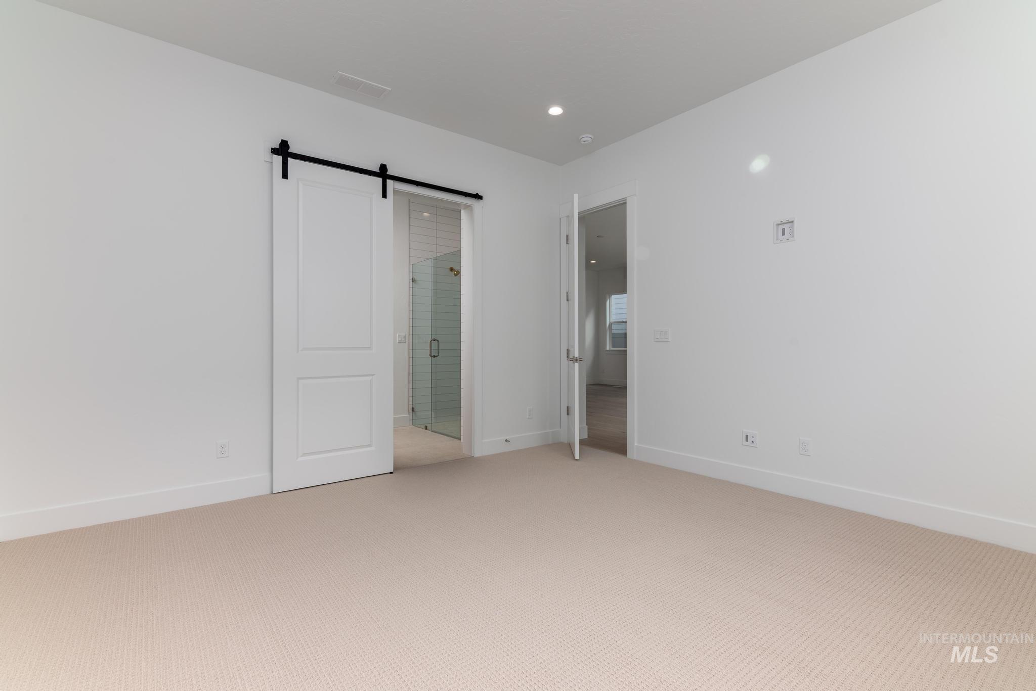 8531 West Chamblee Street Star, ID 83669 - Photo 15 of 37 Unfurnished bedroom with a barn door, light colored carpet, ensuite bathroom, and recessed lighting