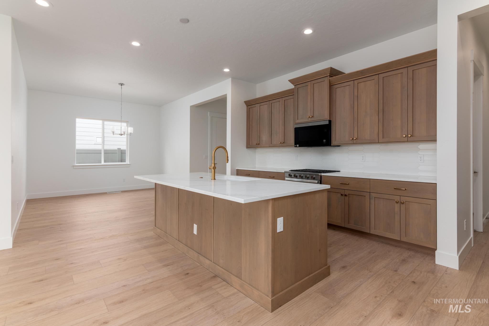 8531 West Chamblee Street Star, ID 83669 - Photo 6 of 37 Kitchen featuring a center island with sink, light wood-style flooring, wood finish cabinets, and gas range