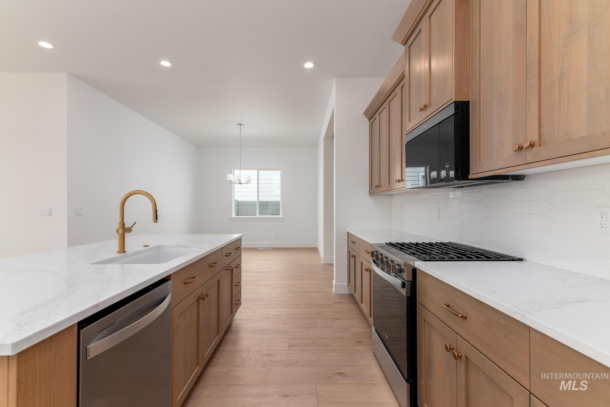 8531 West Chamblee Street Star, ID 83669 - Photo 8 of 37 Kitchen featuring stainless steel appliances, light stone countertops, light wood-style floors, backsplash, and a kitchen island with sink
