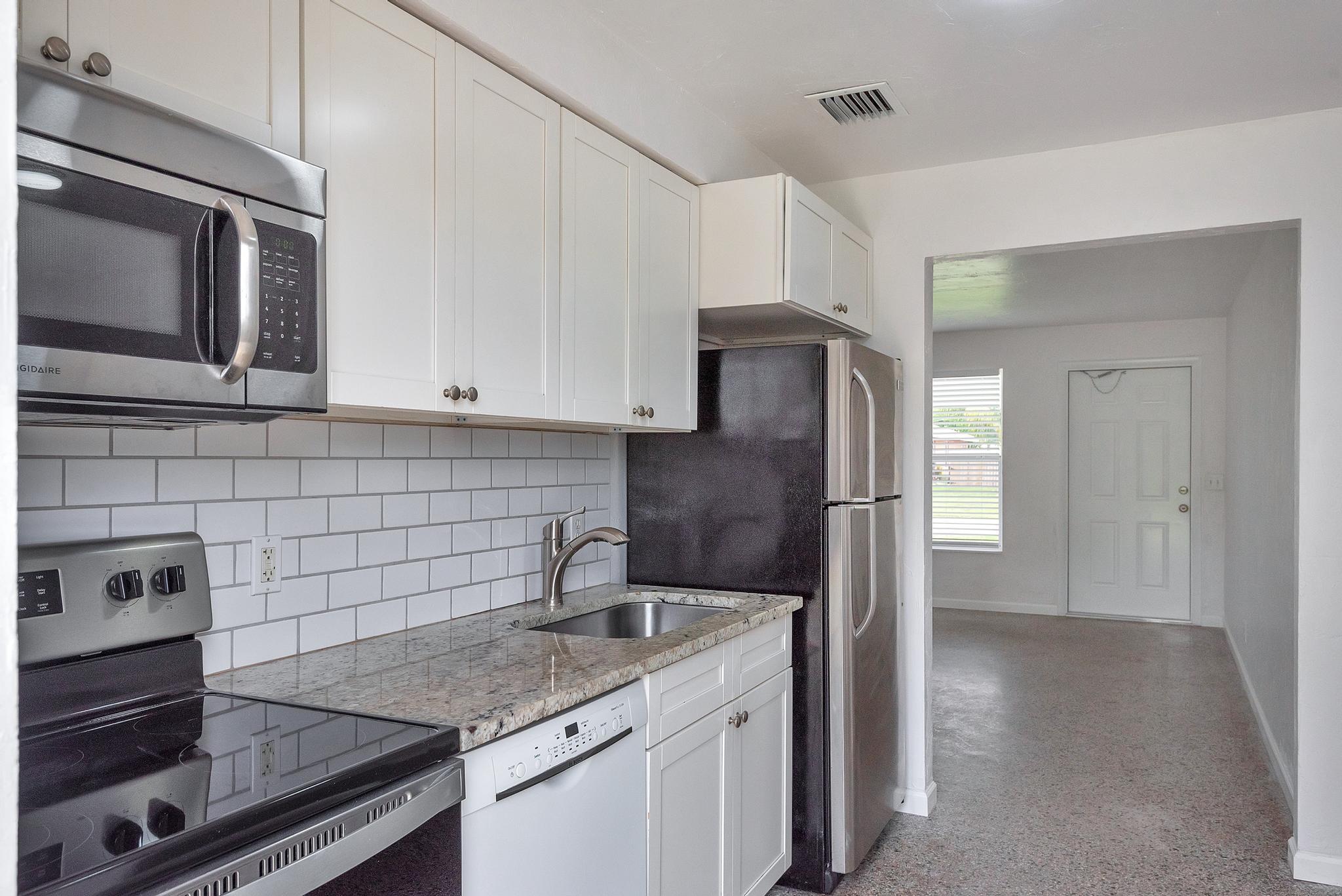 4882 Jefferson Road Delray Beach, FL 33445 - Photo 9 of 41 a kitchen with stainless steel appliances granite countertop a refrigerator and a stove top oven