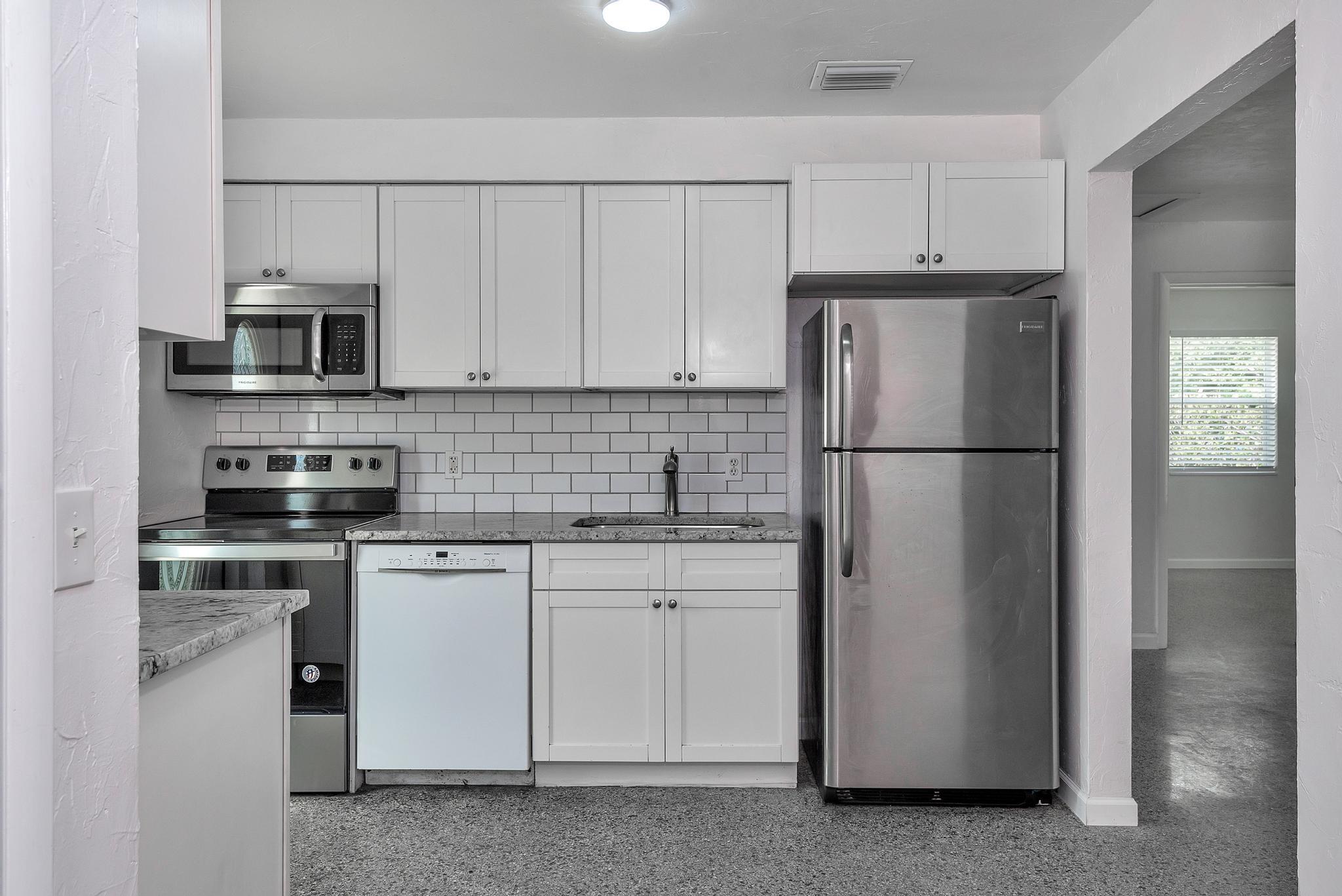 4882 Jefferson Road Delray Beach, FL 33445 - Photo 10 of 41 a kitchen with stainless steel appliances a refrigerator sink and cabinets