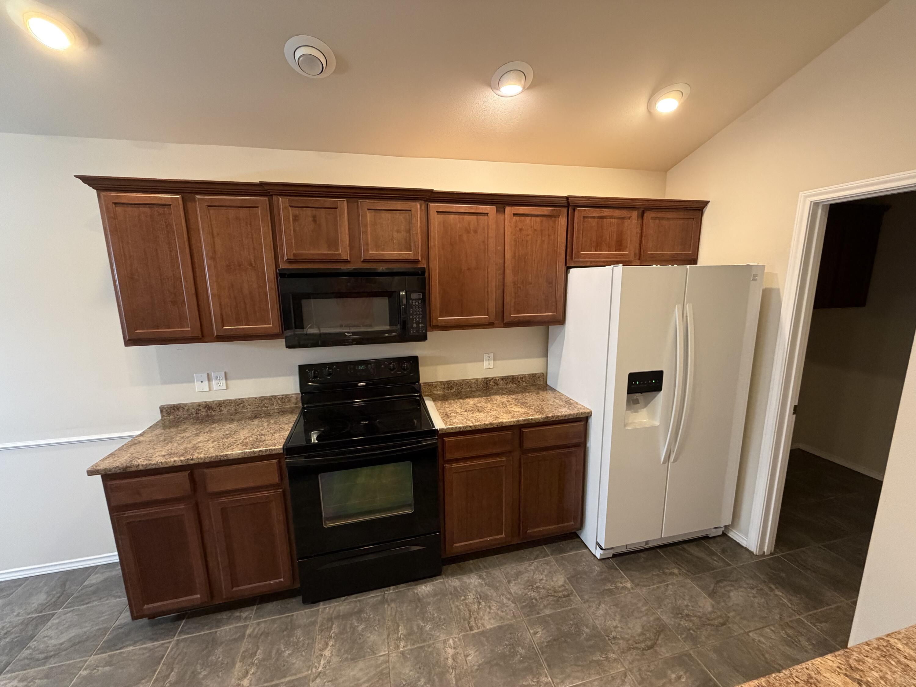 6544 84th Street Lubbock, TX 79424 - Photo 12 of 29 a kitchen with granite countertop a refrigerator and a stove top oven