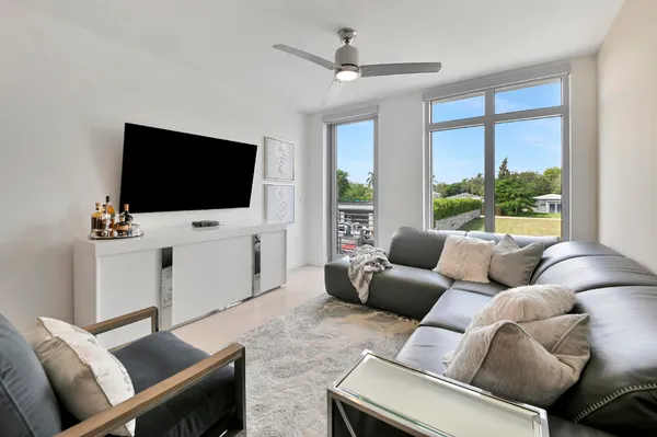 a living room with furniture a flat screen tv and a large window