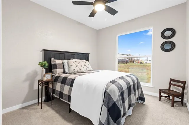 a bed sitting in a bedroom next to a window and a lamp