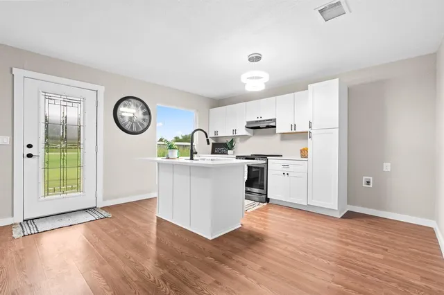 a kitchen with a cabinets a stove a wooden floor and a window