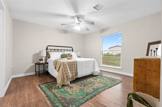 a bedroom with a bed and a dresser with wooden floor