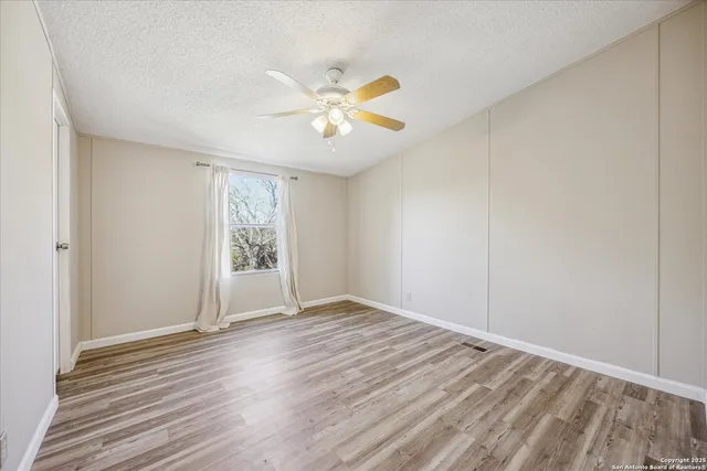 a view of an empty room with window and wooden floor