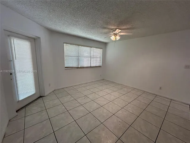 an empty room with windows and ceiling fan