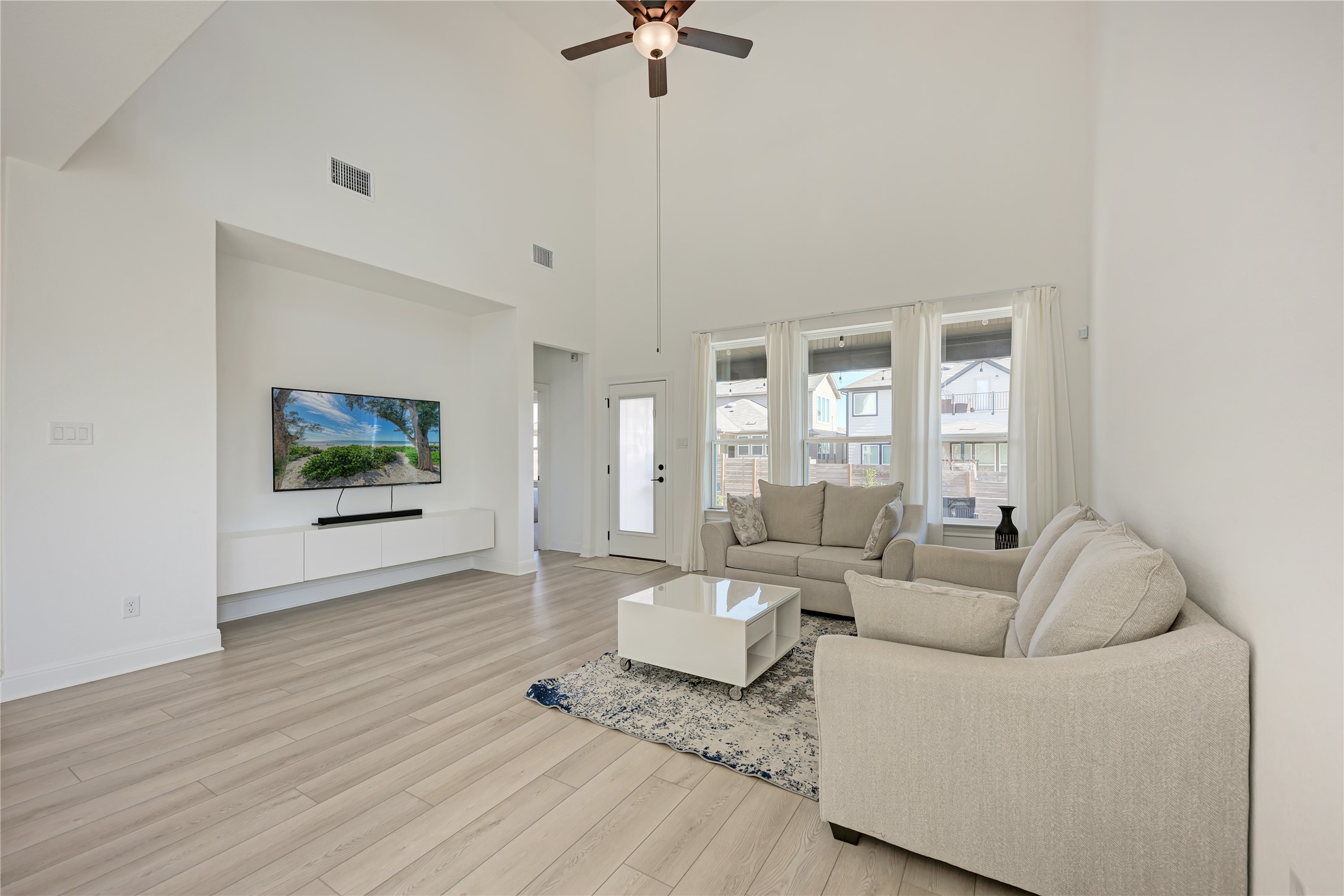 316 Regatta Trail Leander, TX 78641 - Photo 12 of 39 Living area featuring high vaulted ceilings, light wood-finish flooring, recessed lighting, and a prominent media wall with built-in cabinetry