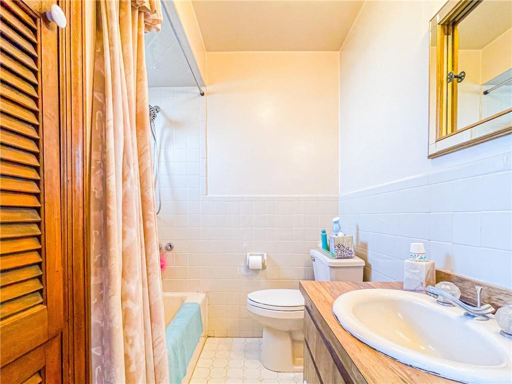 247 82nd Street Brooklyn, NY 11209 - Photo 18 of 48 a bathroom with a sink a toilet and shower curtain