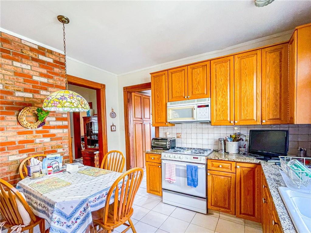 247 82nd Street Brooklyn, NY 11209 - Photo 21 of 48 a kitchen with a refrigerator a stove top oven and a dining table with wooden floor