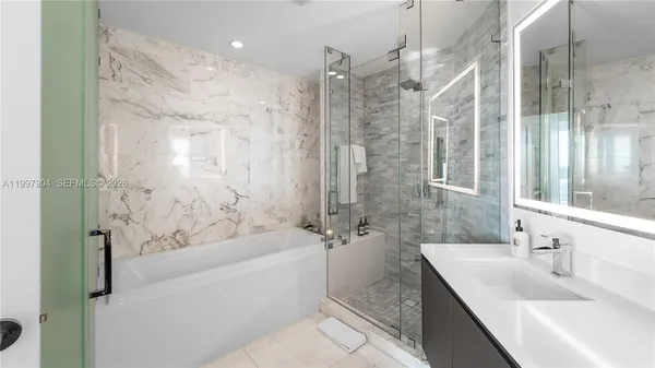 a bathroom with a granite countertop sink a mirror a bathtub and shower