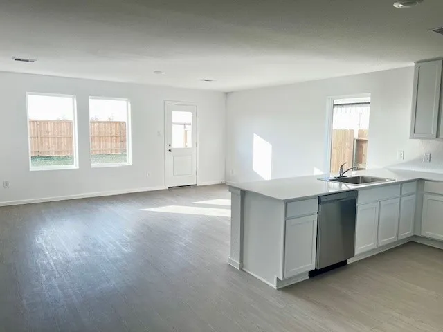 a kitchen with stainless steel appliances granite countertop a stove a sink and white cabinets with wooden floor