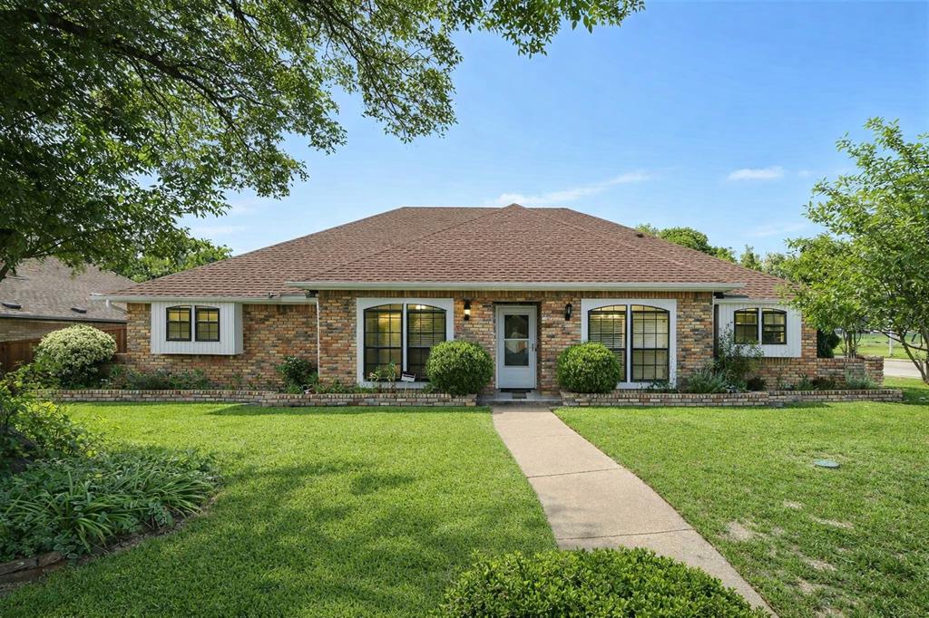 View of front of house with a front lawn, brick siding, and roof with shingles