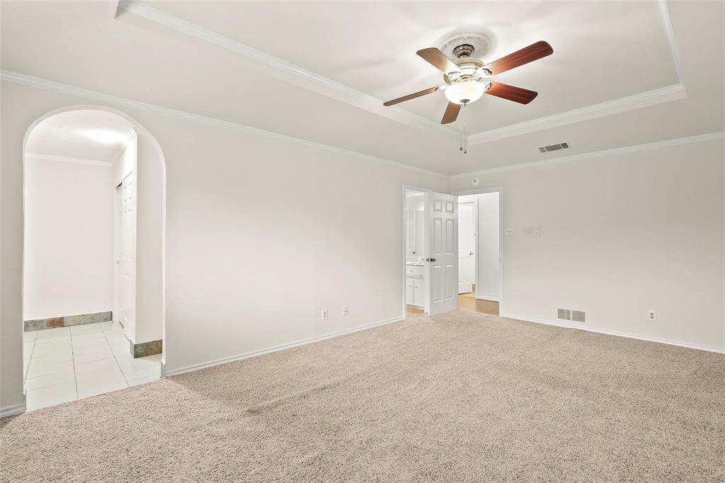 10135 Rita Road Dallas, TX 75243 - Photo 20 of 24 Unfurnished room featuring arched walkways, light carpet, ornamental molding, ceiling fan, and a raised ceiling