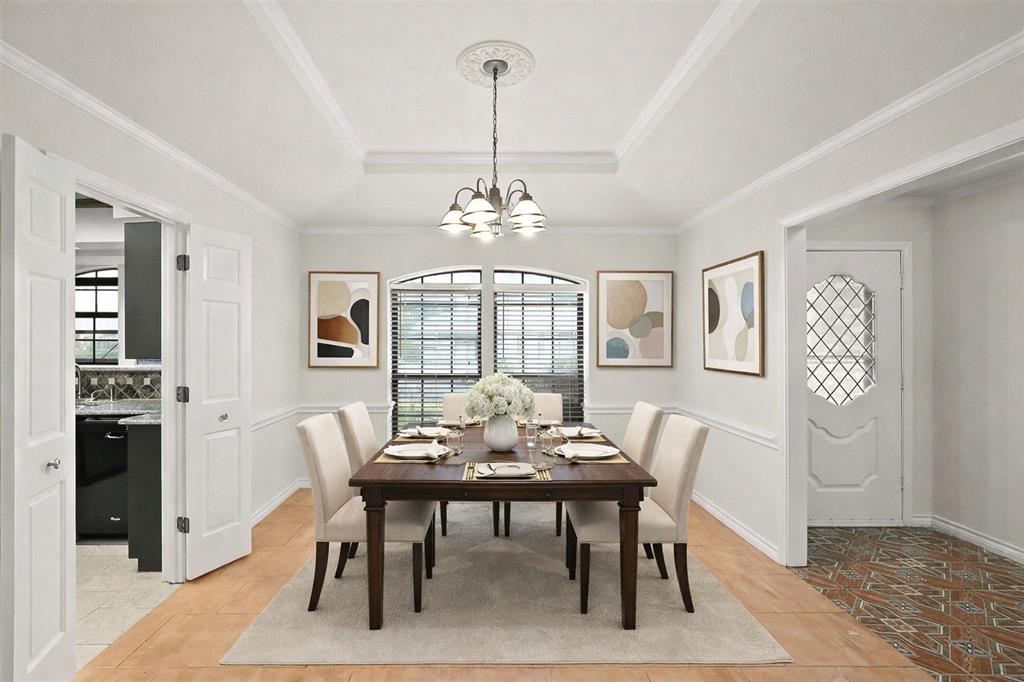 10135 Rita Road Dallas, TX 75243 - Photo 2 of 24 Dining area featuring a tray ceiling, a chandelier, light tile patterned floors, and crown molding