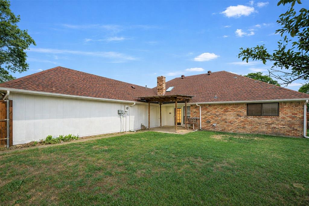 10135 Rita Road Dallas, TX 75243 - Photo 22 of 24 Rear view of property with a patio area, roof with shingles, a lawn, and a chimney