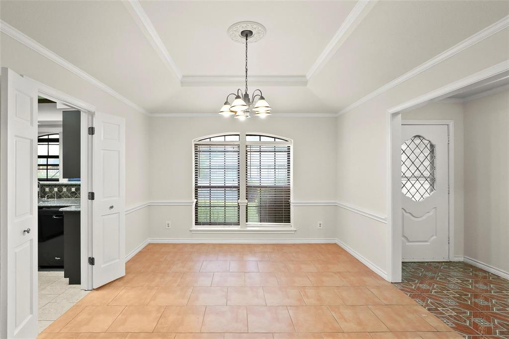 10135 Rita Road Dallas, TX 75243 - Photo 3 of 24 Unfurnished dining area featuring a chandelier, a raised ceiling, light tile patterned floors, and ornamental molding