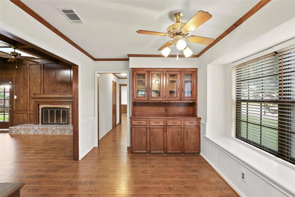 10135 Rita Road Dallas, TX 75243 - Photo 4 of 24 Dining room with ceiling fan, ornamental molding, dark wood-style flooring, and a glass covered fireplace