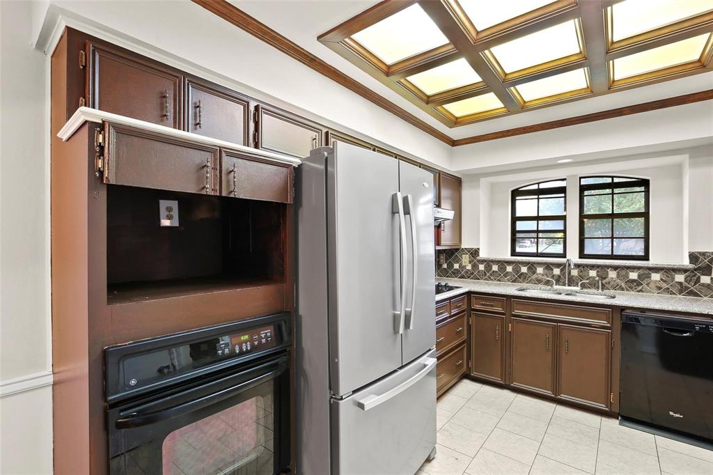 10135 Rita Road Dallas, TX 75243 - Photo 7 of 24 Kitchen featuring black appliances, backsplash, ornamental molding, dark wood finish cabinets, and light stone countertops