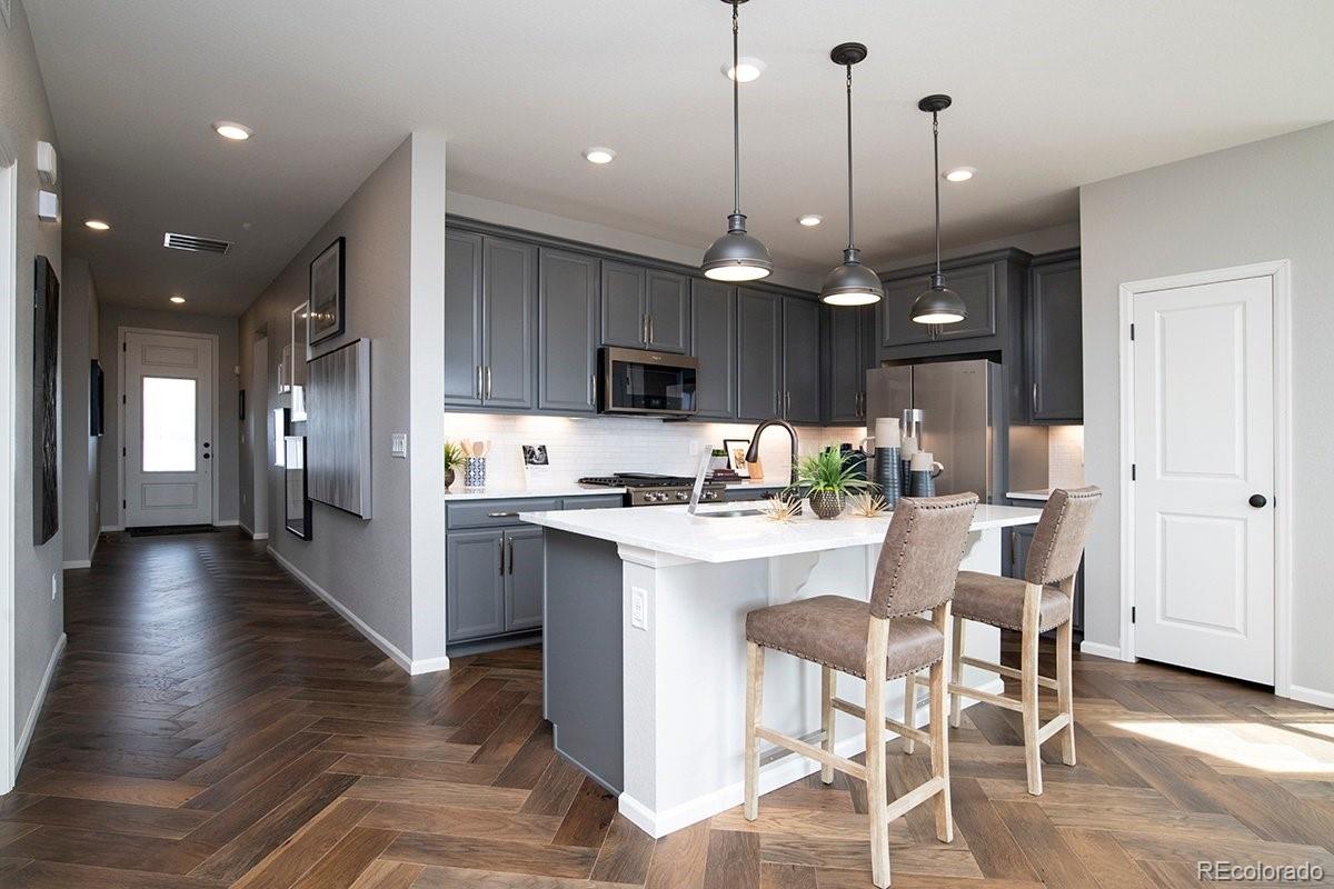 2199 Barela Drive Berthoud, CO 80513 - Photo 8 of 32 a kitchen with stainless steel appliances kitchen island granite countertop a stove top oven a refrigerator a sink and a dining table with wooden floor