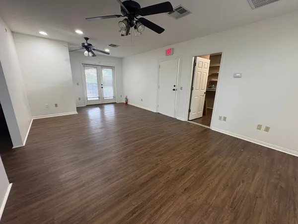 an empty room with wooden floor and windows