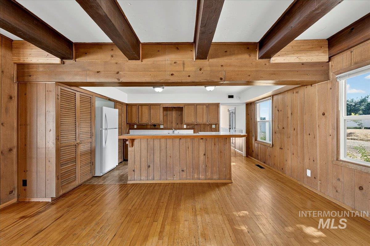 2160 South Five Mile Road Boise, ID 83709 - Photo 17 of 41 Open concept living space featuring wood-finish wall paneling, exposed ceiling beams, and wood-finish flooring