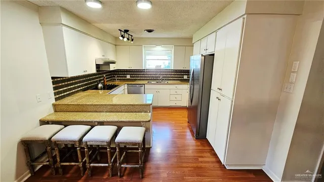 a kitchen with stainless steel appliances granite countertop a refrigerator and a stove top oven