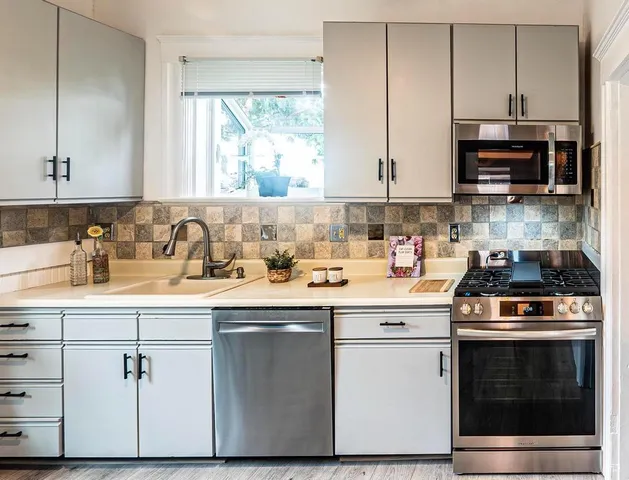 a kitchen with stainless steel appliances granite countertop a stove a sink and a microwave
