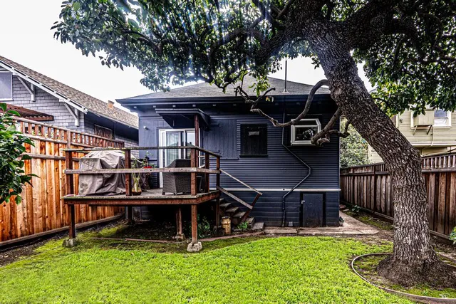 a view of a house with a yard porch and wooden fence
