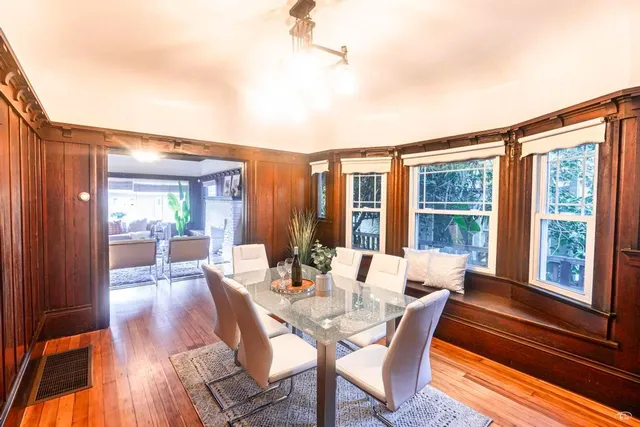 a dining room with furniture large windows and wooden floor