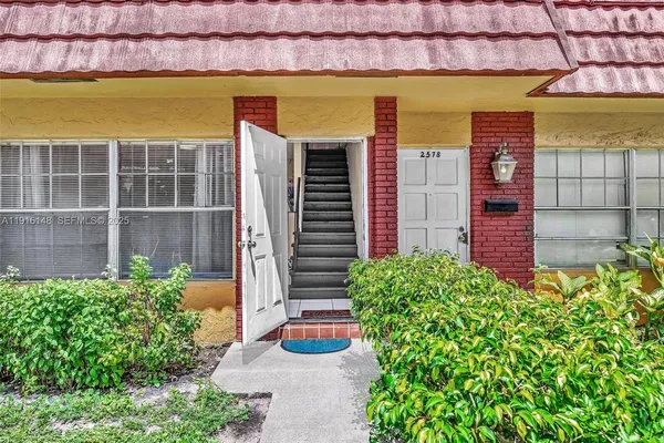 a front view of a house with a yard and potted plants