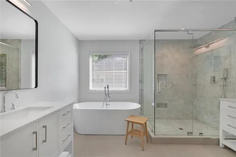a bathroom with a bathtub shower sink and mirror