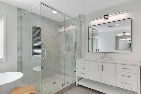 a bathroom with a shower sink vanity and mirror