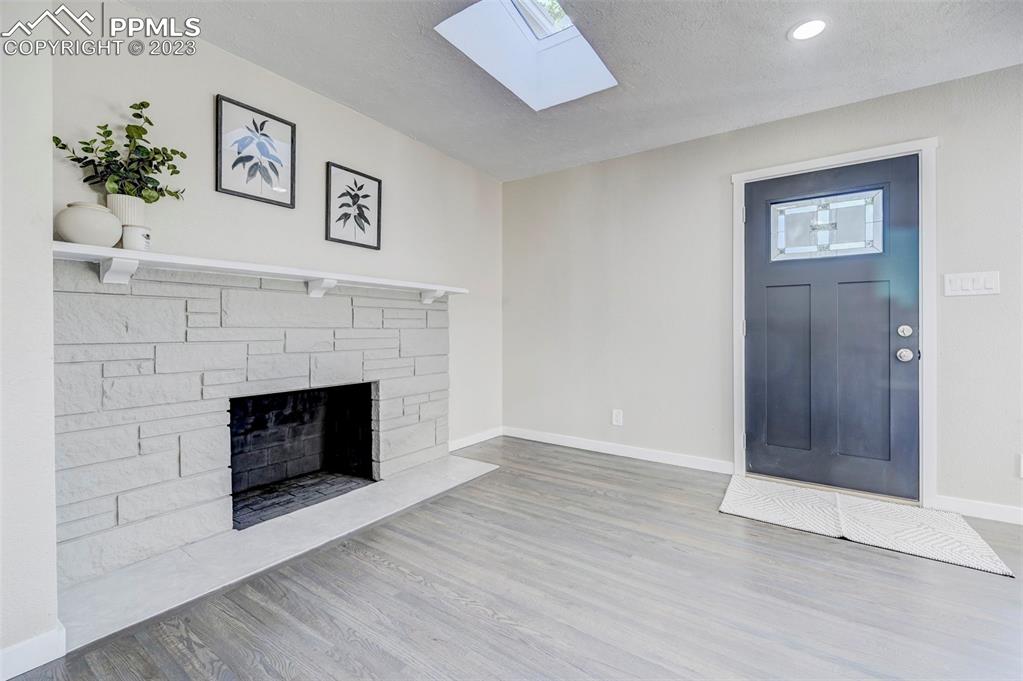 2326 Condor Street Colorado Springs, CO 80909 - Photo 15 of 47 an empty room with a fireplace and wooden floor