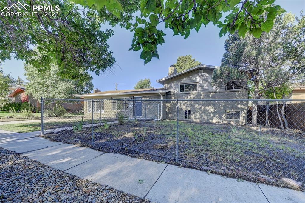 2326 Condor Street Colorado Springs, CO 80909 - Photo 3 of 47 a view of a yard in front of a house with large trees