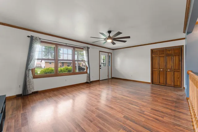a view of an empty room with wooden floor and a window