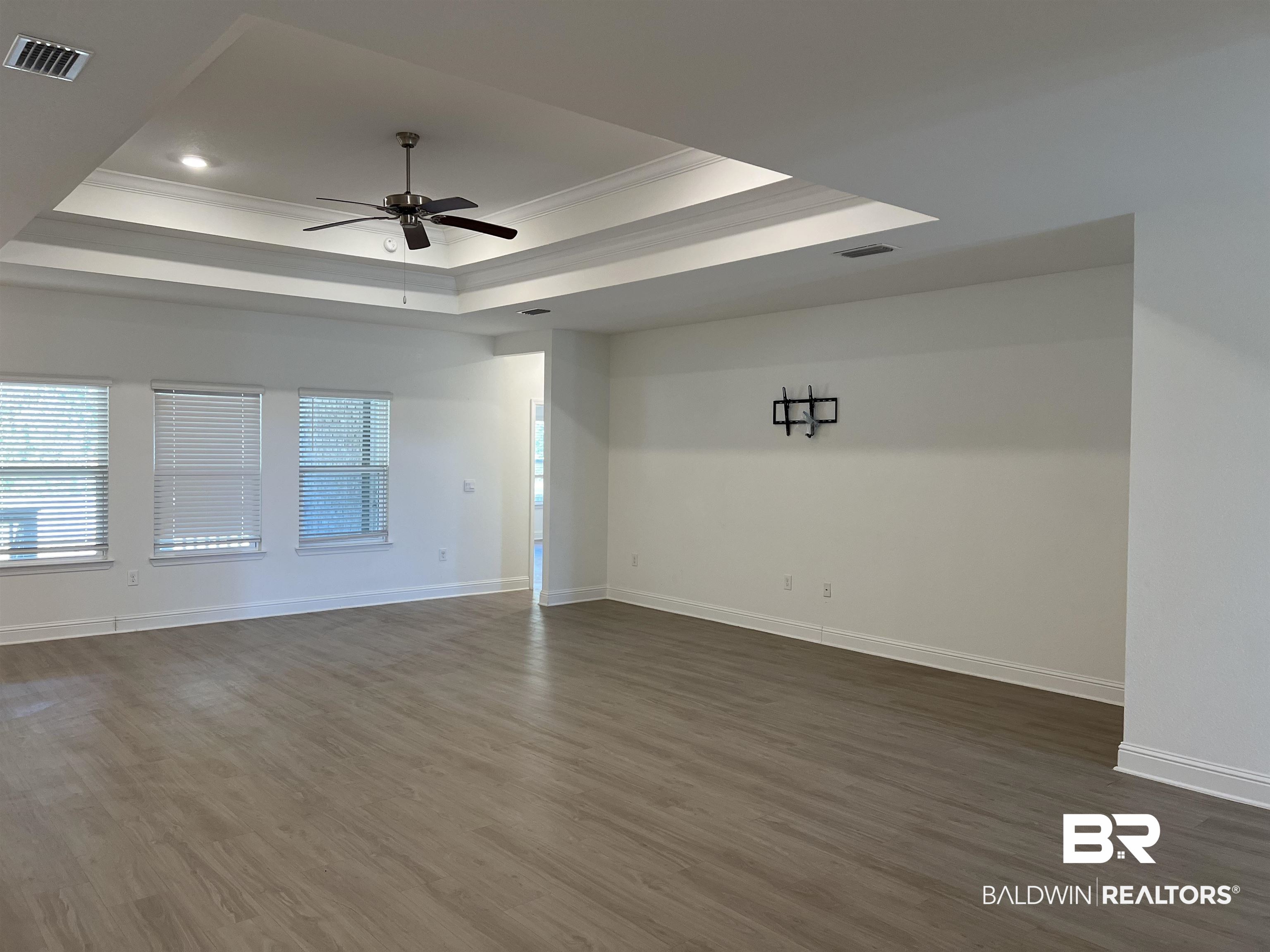 8855 Calverton Street Foley, AL 36535 - Photo 26 of 76 Empty room with dark hardwood / wood-style floors, ceiling fan, crown molding, and a tray ceiling