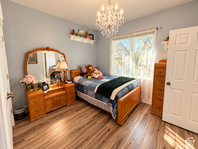 1750 West 4100 North Helper, UT 84526 - Photo 27 of 50 Bright secondary bedroom featuring warm wood-finish flooring, a wooden bed frame, coordinating wood dresser with attached mirror, and abundant natural light from large windows