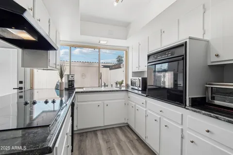 a kitchen with stainless steel appliances granite countertop a refrigerator a stove a sink and a white cabinets